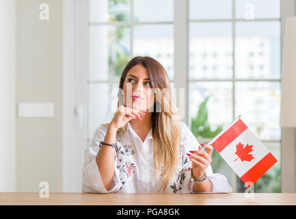 Giovane donna alla home azienda bandiera del Canada faccia seriamente pensando di domanda, molto confusa idea Foto Stock