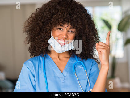 African American donna medico professionista molto felice rivolto con la mano e le dita per lato Foto Stock