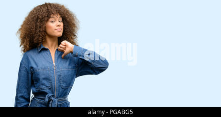 African American donna che indossa tuta blu orgogliosi, eccitato e arrogante, dispositivo di puntamento con la vittoria di fronte Foto Stock