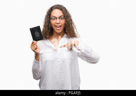 Giovane donna ispanica holding passaporto del Canada con sorpresa faccia puntare il dito a se stesso Foto Stock