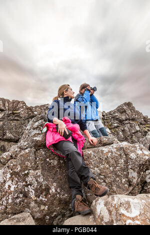 Il fotografo con il suo assistente scatta una foto su rocce laviche nel Parco Nazionale di Pingvellir Islanda Foto Stock