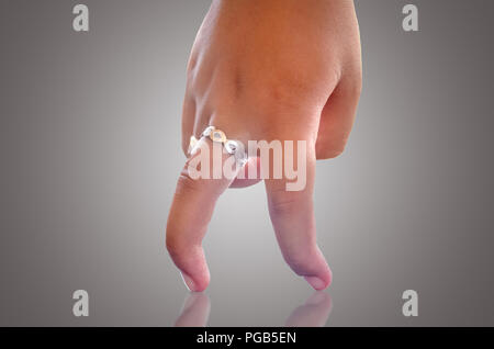 Mano umana che mostra due dita camminando sulla superficie riflettente isolato in uno sfondo grigio Foto Stock