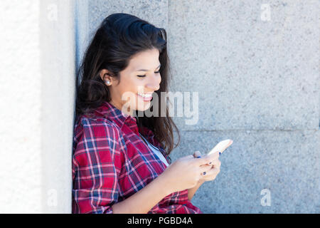 Caucasian donna in abiti casual inviando un messaggio all'aperto in estate Foto Stock