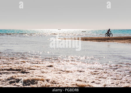 La silhouette di un ciclista solitario sulla spiaggia di Cecina, in Toscana Foto Stock