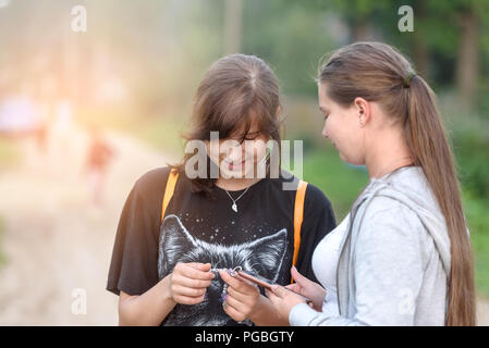 Due ragazze con i telefoni cellulari nelle loro mani, il concetto di amicizia e di comunicazione Foto Stock