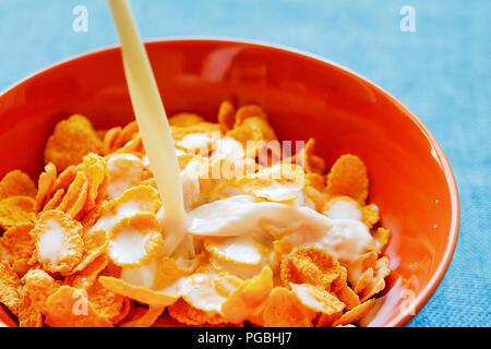 Fiocchi di cereali e latte in un vaso di argilla. La prima colazione. Foto Stock