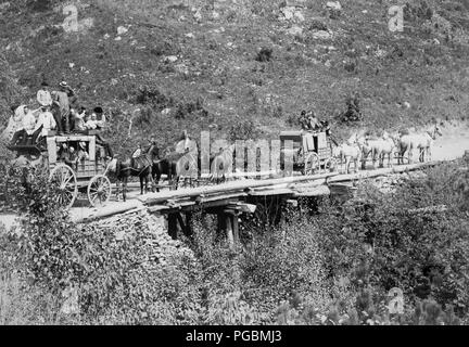 Due stagecoaches attraversando un ponte; gli uomini in carri sono di ondulazione o il ribaltamento di loro cappelli per il fotografo. Foto Stock