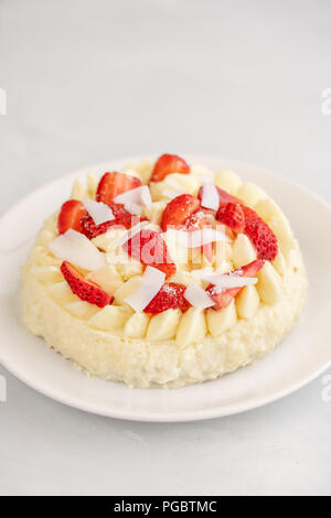 Delicato Strawberry Cheesecake con noce di cocco. Deliziosi dolci fatti in casa con frutti di bosco freschi sul tavolo luminoso. Foto Stock