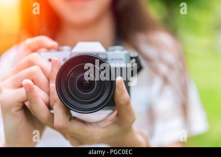 Primo piano frontale della lente della fotocamera mirrorless nella donna la teen fotografo Foto Stock