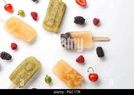 Immagine sulla sommità di frutta congelata ghiaccio, uva spina, mora, ciliegia sullo sbozzato sullo sfondo bianco. Foto Stock