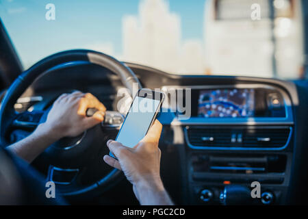 Chiusura del giovane uomo guardando il navigatore GPS dietro la ruota in auto. L uomo è messa a fuoco e il colore di primo piano e auto è su sfondo e sfocata. Vista posteriore Foto Stock