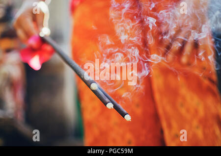 Bella donna asiatica holding bastoncini di incenso e pregando durante la cerimonia Indù in un tempio a Bali, in Indonesia Foto Stock