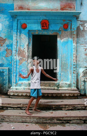 Kid sta davanti a una porta in Caranasi, India Foto Stock