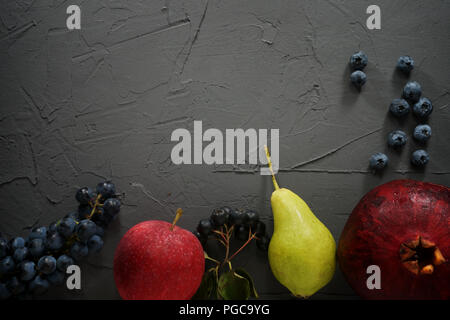 Varie estate freschi frutti e bacche. Pera, mela, blu uva, mirtilli, melograno e aronia su sfondo nero. Banner di frutta. Foto Stock