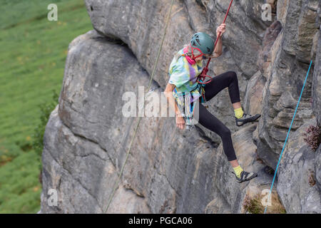 08.01.2018.Stanage bordo,Derbyshire,Uk.senior attivo.donna matura-rocciatore di scendere lungo la scogliera attaccato alla fune di sicurezza.paesaggio sfocata in b Foto Stock