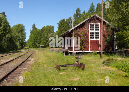 Vecchio, rosso, edificio di legno accanto alla ferrovia. Carrello questo lato molla. Foresta. Foto Stock