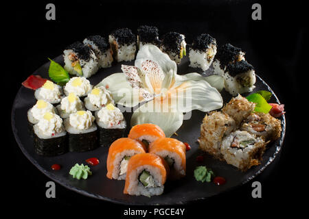 Seth sushi su uno sfondo nero.menu del ristorante giapponese. Diversi sushi steso su una piastra con salsa allo zenzero wasabi. Rotoli da sopra Foto Stock