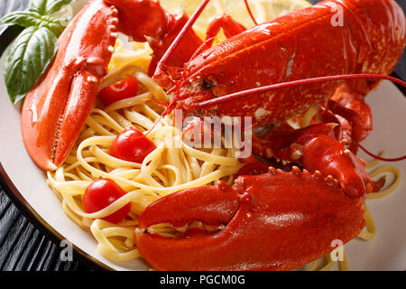 Bellissimi frutti di mare con spaghetti e aragosta bollita, pomodoro, limone e erbe aromatiche fresche di close-up servita su una piastra orizzontale. Foto Stock