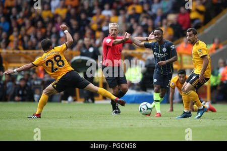 Manchester City's Raheem Sterling passa attraverso Wolverhampton Wanderers' Joao Moutinho e Raul Jimenez durante il match di Premier League a Molineux, Wolverhampton. Foto Stock