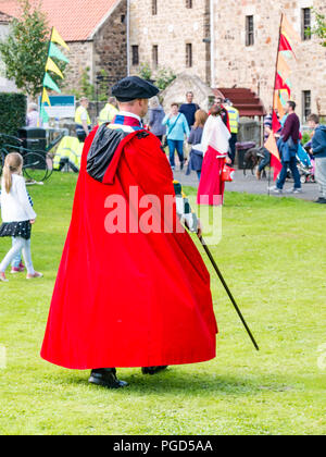 Haddington, Scozia, Regno Unito. 25 agosto 2018. Haddington 700 festeggiamenti Medieval Big Day, il Medieval Day è il momento culminante degli eventi di Haddington 700 che si svolgono nel 2018 per celebrare la concessione di una carta di Robert the Bruce alla città nel 1318, confermando il diritto di Haddington di tenere un mercato e di raccogliere le dogane. Un uomo vestito in costume medievale rosso mantello Foto Stock