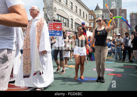 Jersey City, Stati Uniti d'America. Il 25 agosto, 2018: Elizabeth Schedl (a destra), Chief Operations Officer a Hudson Centro di orgoglio, marche con la sua bandiera LGBT sollevato durante la diciottesima edizione Jersey City LGBT Pride Festival in Jersey City, Stati Uniti d'America. Credito: Jonathan Carroll/Alamy Live News Foto Stock