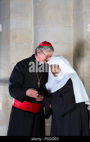 Suora cattolica e il cardinale parlando in una chiesa medievale Foto Stock