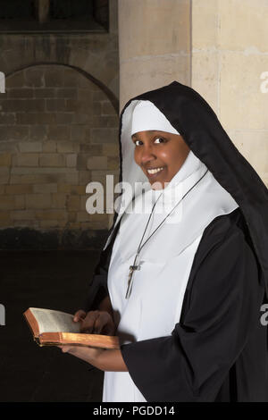 Sorridente nun leggendo la Bibbia in una chiesa medievale Foto Stock
