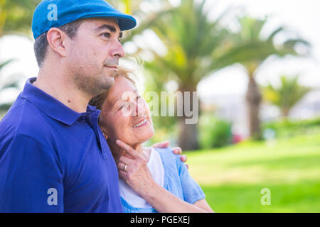 Differenti età matura come madre e figlio stare abbracciati insieme all'esterno le attività per il tempo libero con amore ed emozioni. Godetevi la giornata nel parco con gree Foto Stock