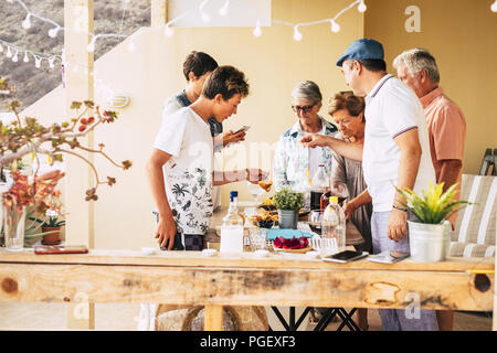 Gruppo di persone differenti età da adolescente matura per divertirsi insieme mangiare e bere in amicizia a casa all'aperto in terrazza. mix Foto Stock