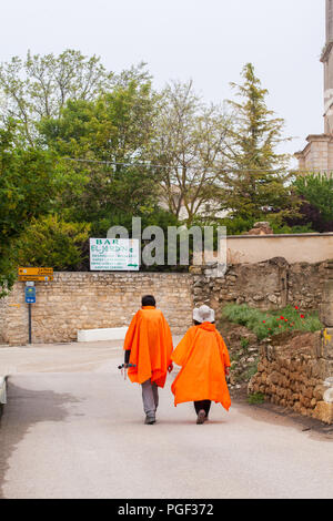 Due pellegrini che indossano poncho arancione bagnato tempo capes camminare nella città di Castrojeriz mentre si cammina il Camino de Santiago la strada di San Giacomo Foto Stock