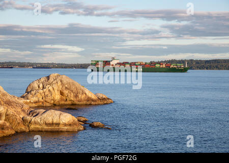 Baia a ferro di cavallo, West Vancouver, British Columbia, Canada - 25 Giugno 2018: caricato completamente il trasporto merci nave è passando per la costa rocciosa durante una vibr Foto Stock