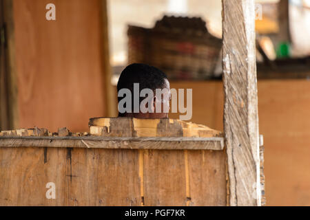 A Lomé, Togo - Jan 9, 2017: Non identificato uomo Togolese da dietro alla porta di Lome. Il Togo di persone soffrono di povertà a causa di una cattiva economia Foto Stock