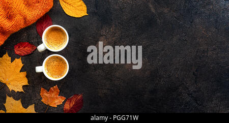 Vista dall'alto di due tazze di caffè intorno a foglie di giallo Foto Stock