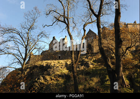 Il Castello di Edimburgo, in Scozia, si trova in alto su Castle Rock. Visto attraverso gli alberi sotto in una giornata limpida Foto Stock