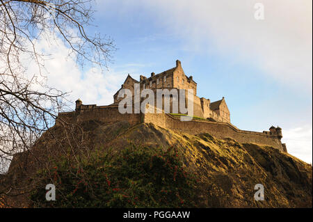 Il Castello di Edimburgo, in Scozia, si trova in alto su Castle Rock. Visto attraverso gli alberi sotto in una giornata limpida Foto Stock