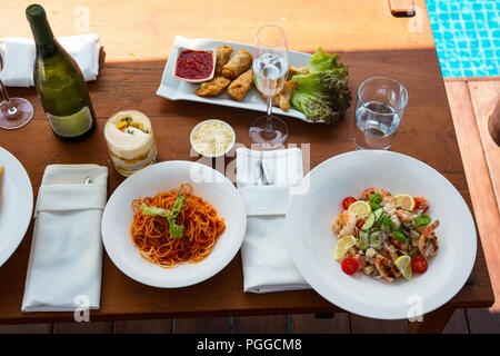 Vista superiore del delizioso spaghetti alla bolognese e insalata di gamberetti serviti per pranzo al resort di lusso o ristorante Foto Stock