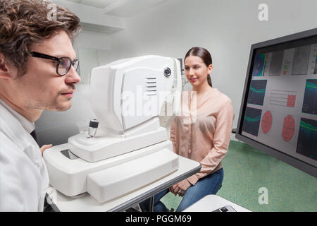 Oculista in occhi clinic esaminare retinale funzione visiva con un PTOM SLO macchina Foto Stock