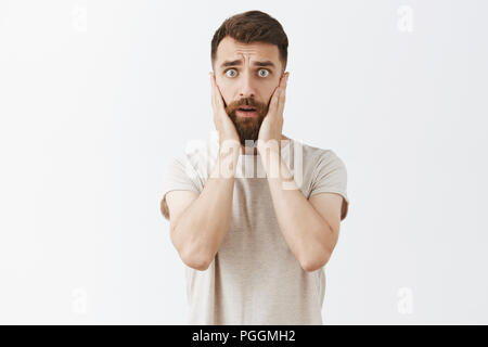 Ritratto di bello ed elegante imprenditore maschio a partire alla ricerca di panico interessati e preoccupati tenendo le mani sul viso e lo sguardo disperato in telecamera di perdere un sacco di soldi in mancanza sul meeting aziendale Foto Stock