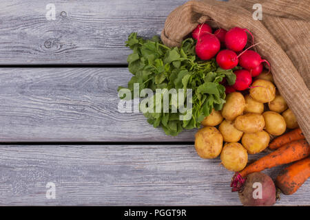 Borsa di tela con vari ortaggi. Grigio backgorund di legno. Spazio libero per il testo, copiare lo spazio. Foto Stock