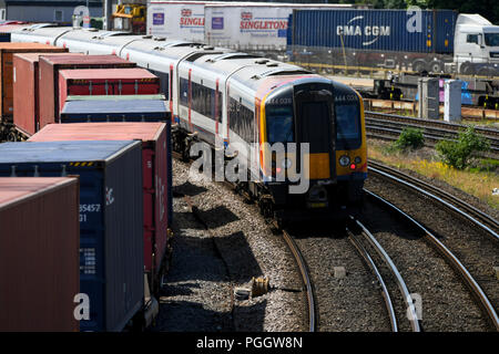 A South Western Railway treno passa un contenitore di treno sulla linea principale in viaggio verso Southampton. Foto Stock