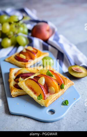 Frutto della pasta sfoglia torte con fette di pesche, susine e uva Foto Stock