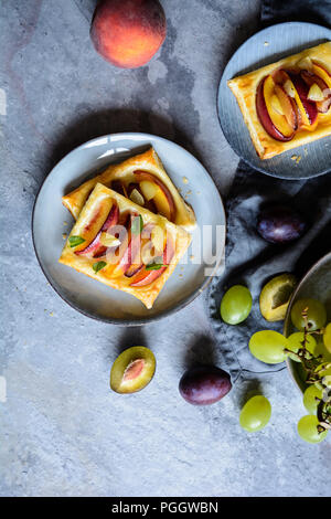 Frutto della pasta sfoglia torte con fette di pesche, susine e uva Foto Stock