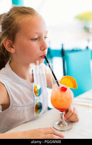 Adorabile bambina di bere succo tropicale mocktail a outdoor cafe sul giorno di estate Foto Stock