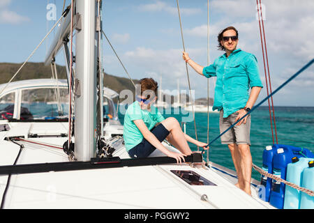 Il padre e il suo figlio adolescente a bordo di yacht a vela avente estate Viaggi avventura Foto Stock