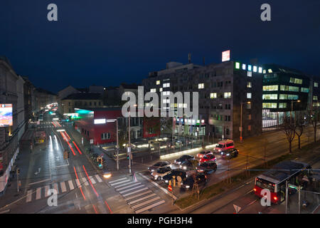 Il traffico notturno sul Waehringer Guertel Road intersezione con Gentzgasse vista aerea. WKO e WIFI del campus in background. Foto Stock