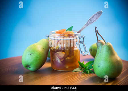 Dolce frutta marmellata di mele e pere in un vasetto di vetro su uno sfondo blu Foto Stock