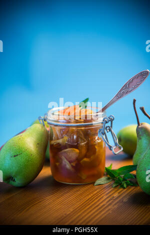 Dolce frutta marmellata di mele e pere in un vasetto di vetro su uno sfondo blu Foto Stock