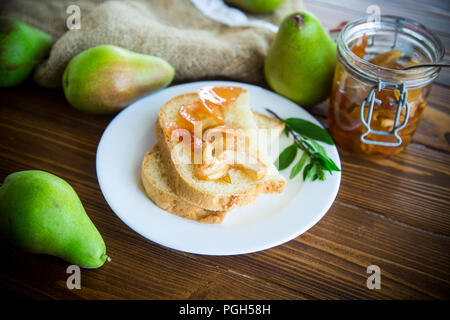 Pezzi di pane con dolci fatti in casa a base di marmellata di frutta da pere e mele in un piatto su un tavolo di legno Foto Stock