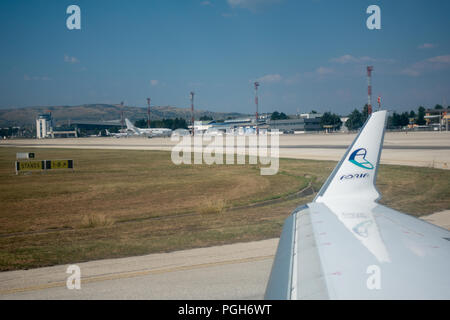 Skopje, Macedonia - 25 agosto 2018: vista attraverso la finestra aereo sul parafango del velivolo, Adria Airways logo sulla punta ala e Skopje airport Foto Stock