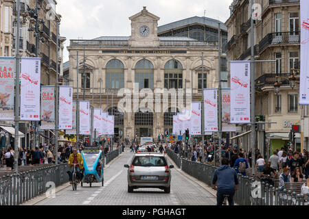 Lille, Francia - 15 Giugno 2018: il traffico e la gente che camminava sul Faidherbe Street. Stazioni ferroviarie di Lille-Flandres railroad station sullo sfondo. Foto Stock